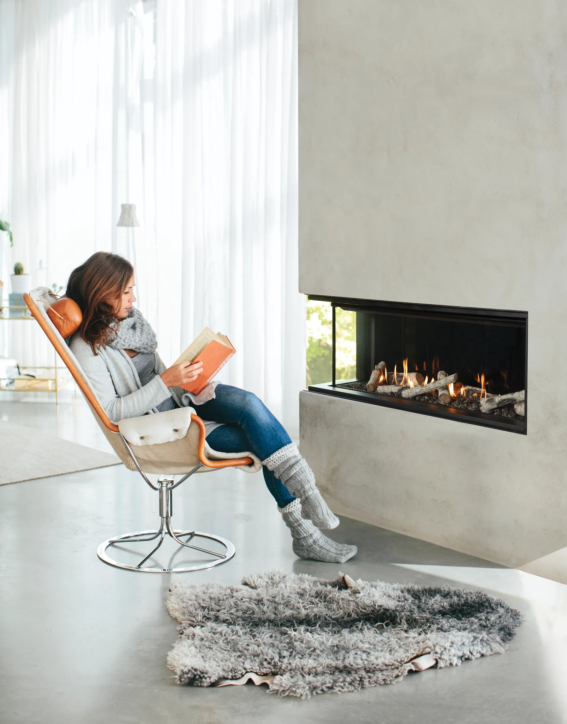 Woman reading by a linear gas fireplace in a quiet Wisconsin living room