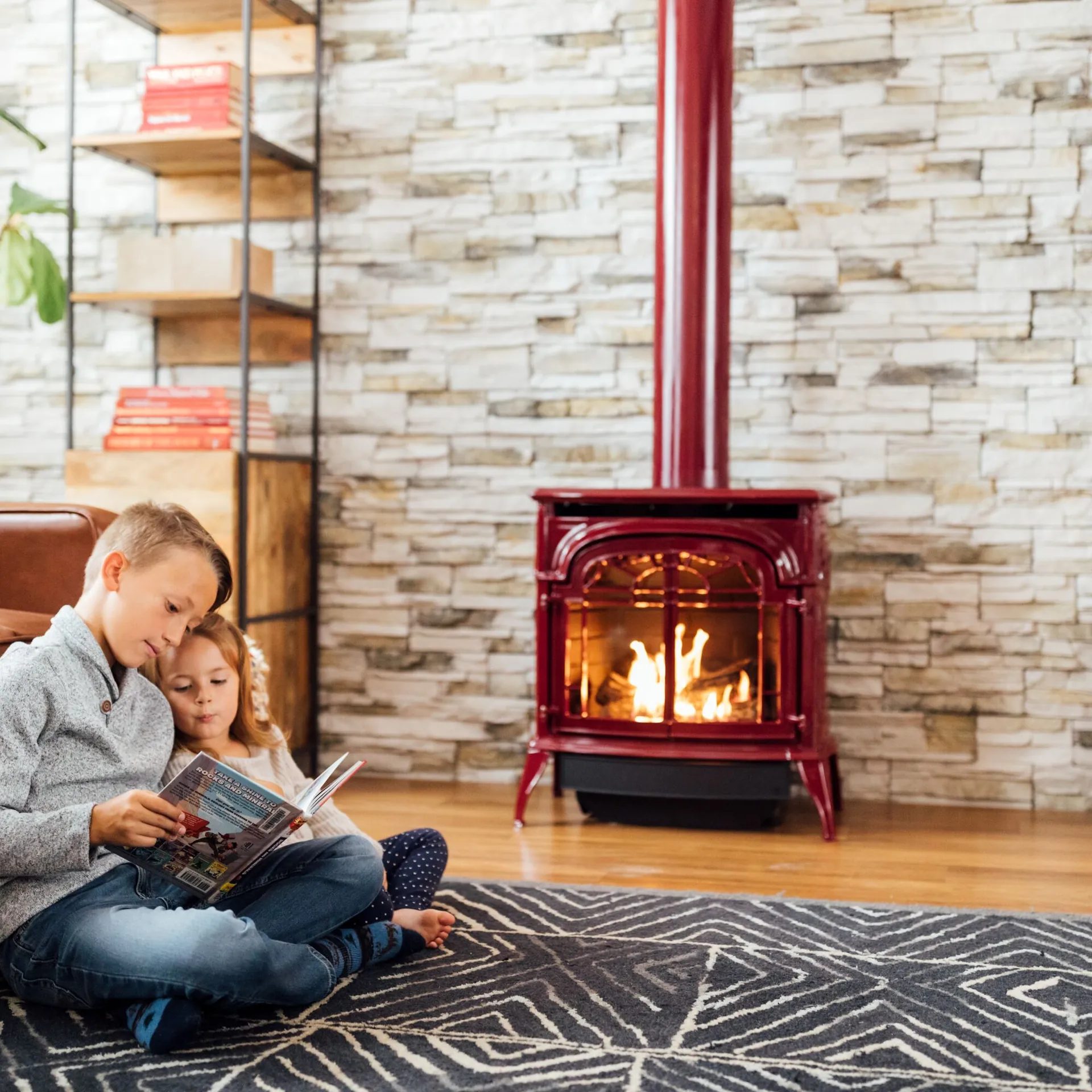 Siblings reading together by a Valor gas fireplace