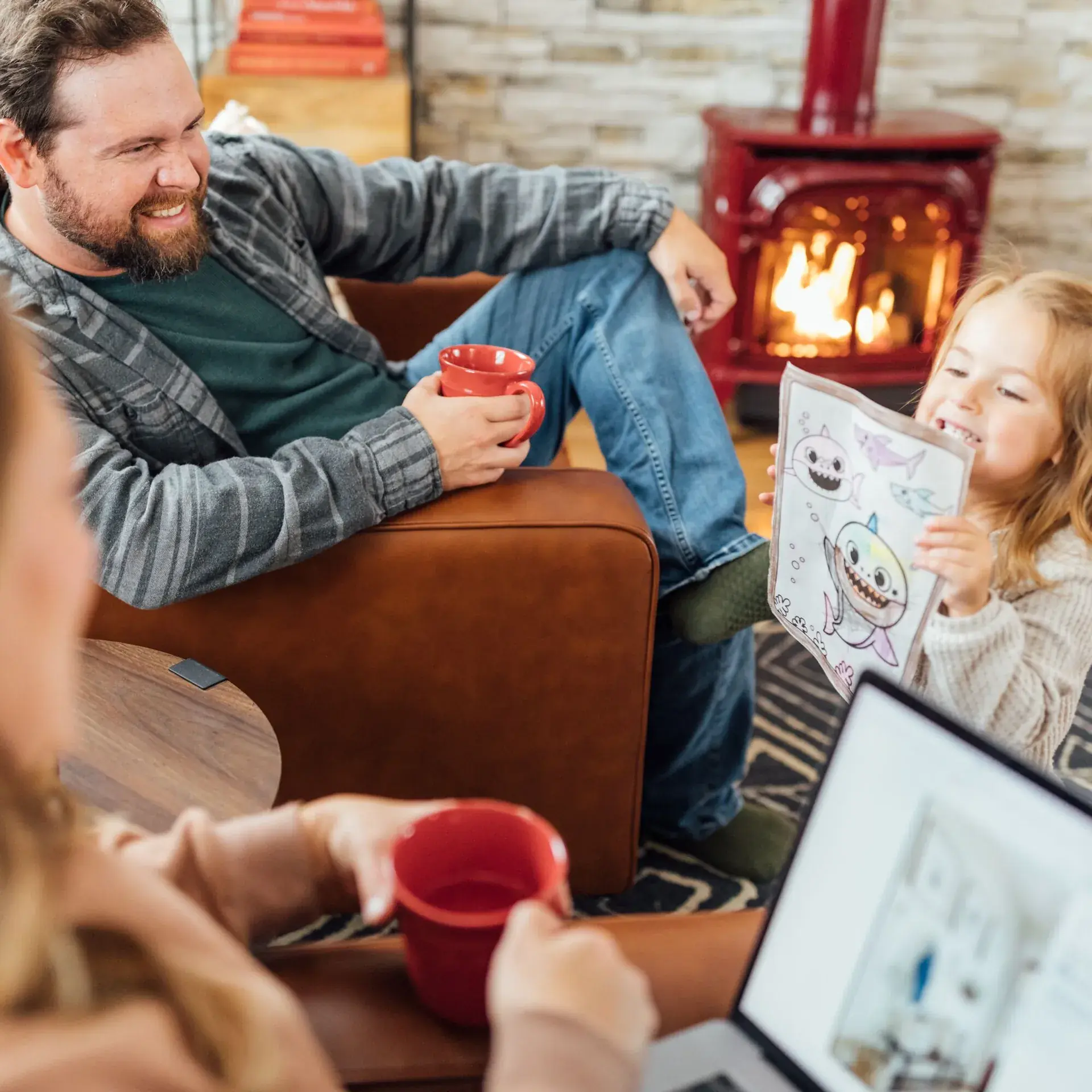 Family on couch coloring together near a lit gas fireplace