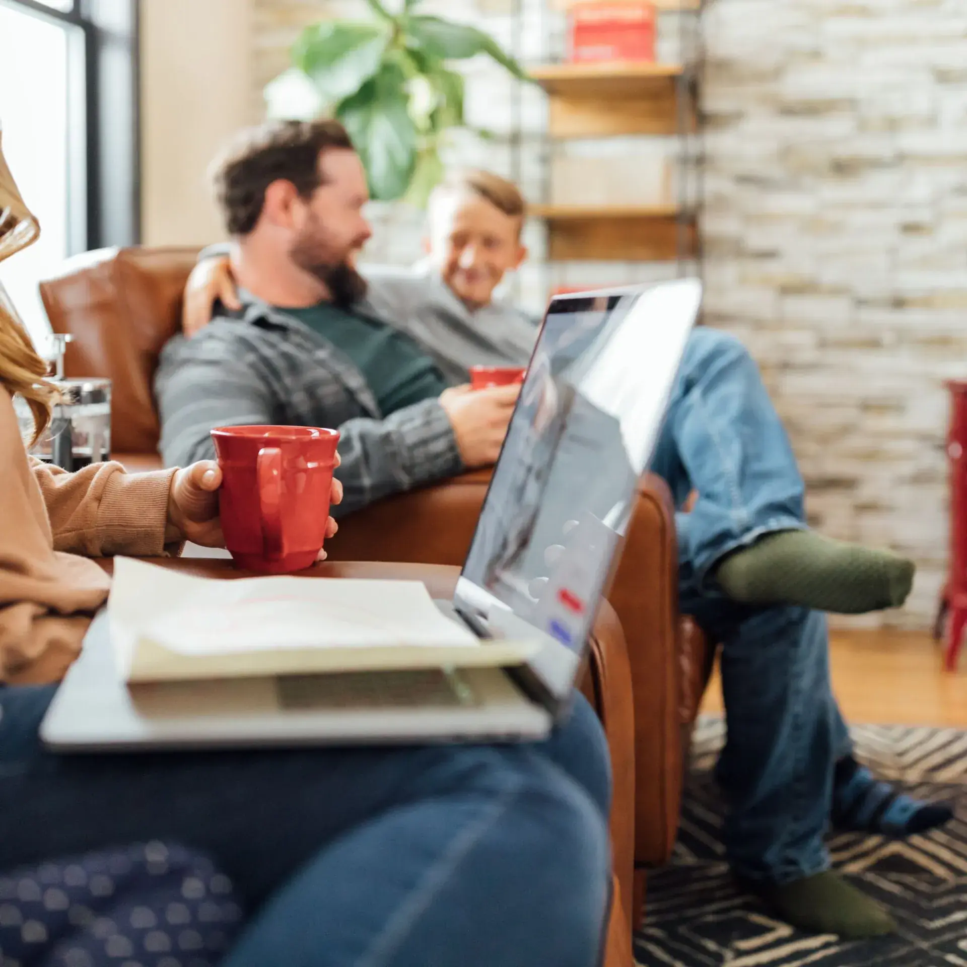 Family relaxing on couches with laptop near a Wisconsin fireplace
